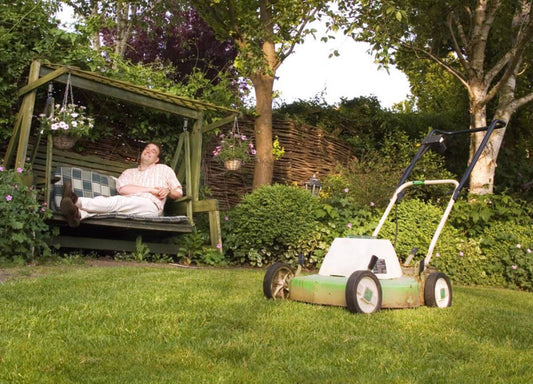 A man resting on the bench done mowing the lawn