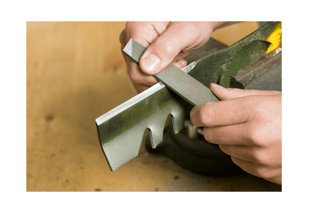a man sharpening the mower blade with the file
