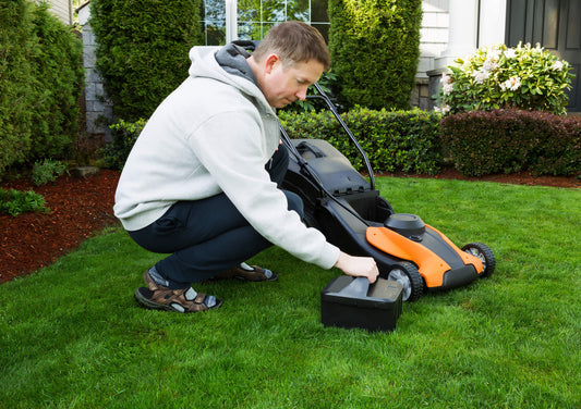 Mature man putting battery into electric Lawn Mower