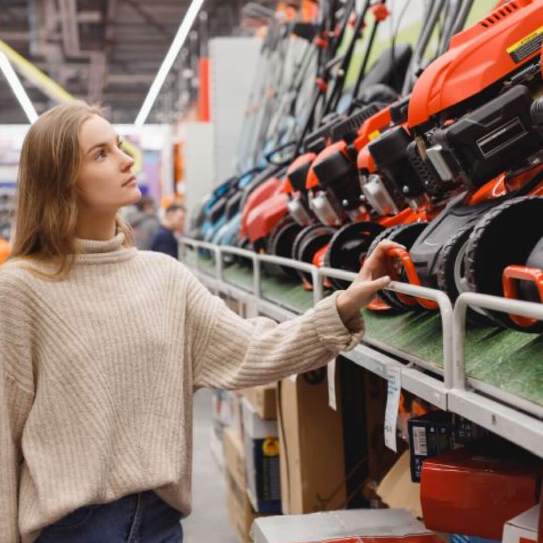 A woman choosing a lawn mower at the store